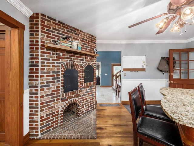 767 London Groveport Rd, Lockbourne, OH 43137 - dining room with a brick fireplace, ornamental molding, wood finished floors, and a wainscoted wall