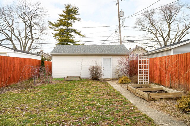 view of yard featuring a garden, a fenced backyard, and an outbuilding