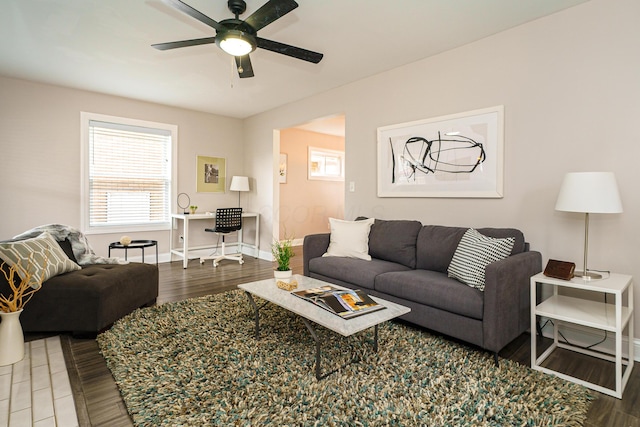 living room with a ceiling fan, baseboards, and wood finished floors