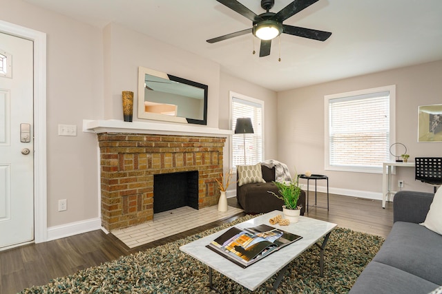 living area featuring a brick fireplace, baseboards, and wood finished floors