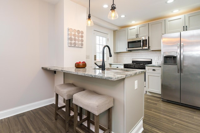 kitchen featuring stainless steel appliances, dark wood-type flooring, a sink, and light stone counters