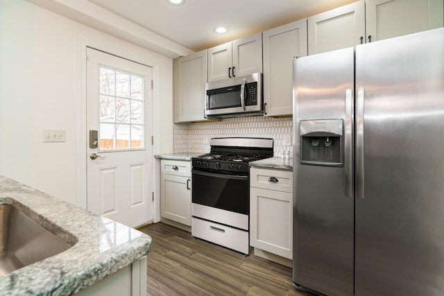 kitchen featuring light stone counters, dark wood finished floors, recessed lighting, backsplash, and appliances with stainless steel finishes