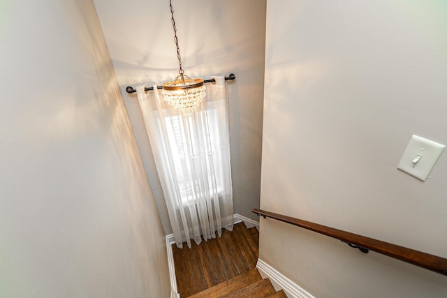 staircase featuring a chandelier, wood finished floors, and baseboards