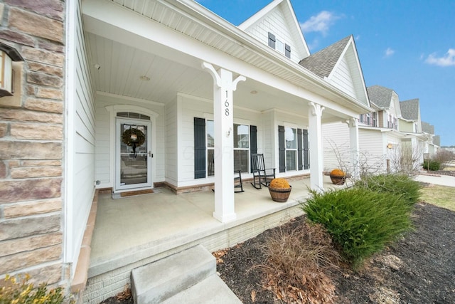 view of exterior entry with covered porch and roof with shingles