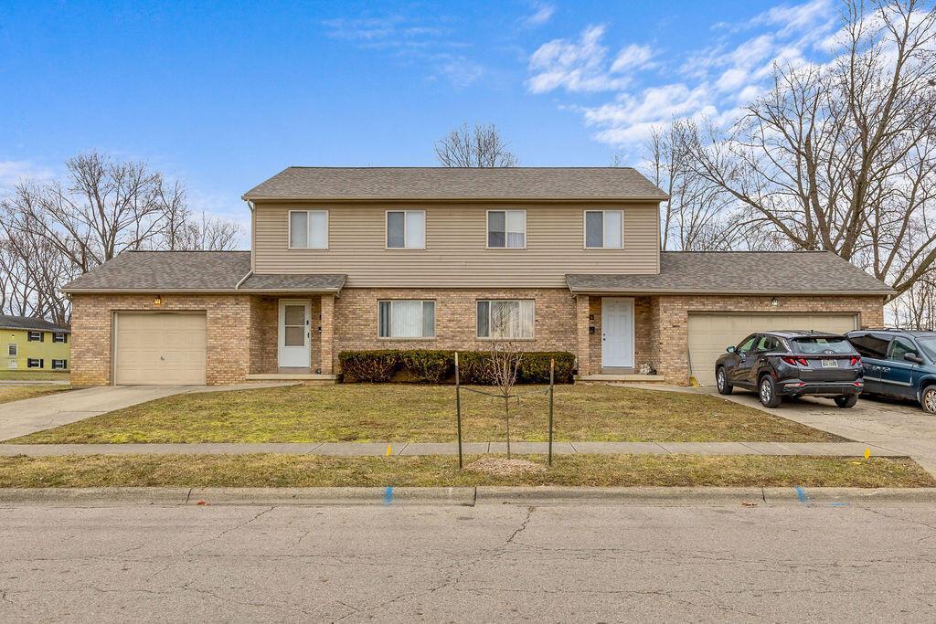 view of front of home with a garage, brick siding, and driveway