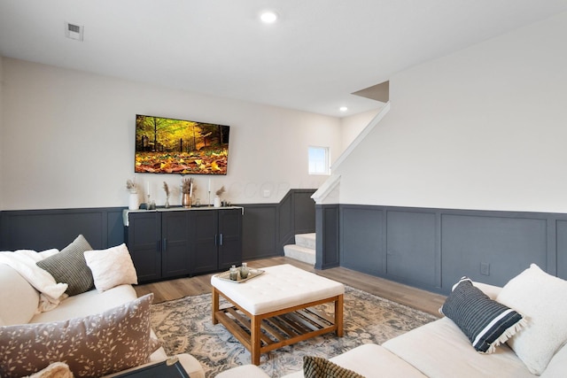 living area featuring visible vents, wainscoting, light wood-style flooring, stairway, and recessed lighting