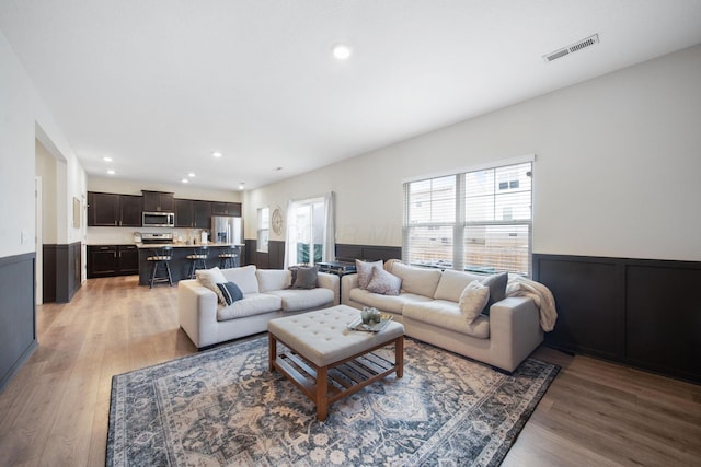 living room featuring visible vents, wainscoting, light wood-style flooring, and recessed lighting