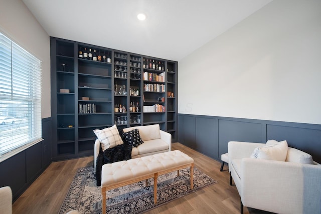 living area featuring wainscoting, a decorative wall, and wood finished floors