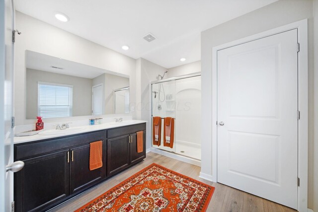 bathroom featuring double vanity, a sink, visible vents, and a shower stall