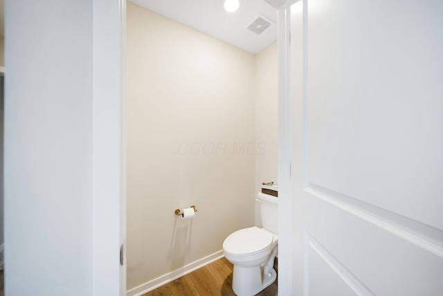 bathroom with baseboards, visible vents, toilet, and wood finished floors