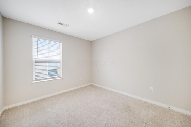 carpeted spare room featuring baseboards and visible vents