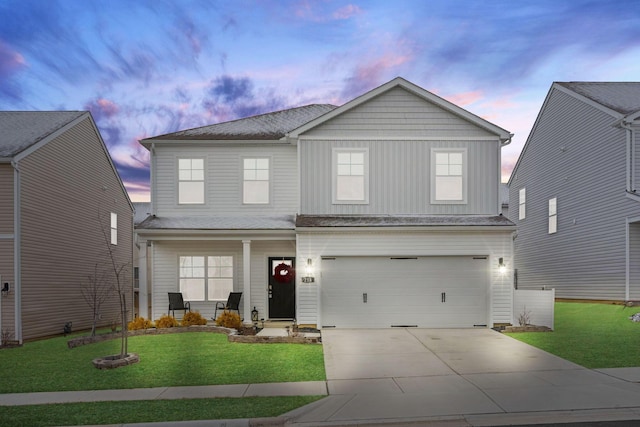 traditional home featuring a garage, concrete driveway, covered porch, a yard, and board and batten siding