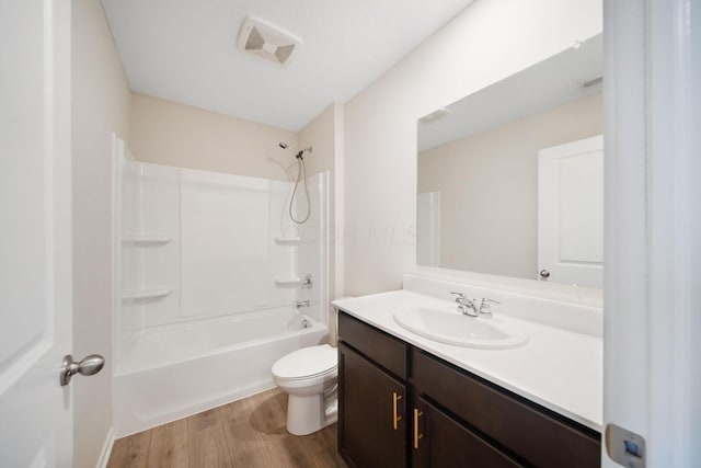 bathroom with toilet, wood finished floors, vanity, visible vents, and  shower combination