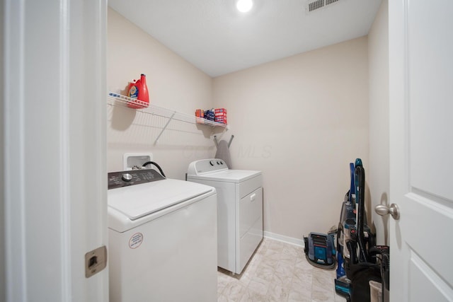 clothes washing area with washer and dryer, laundry area, visible vents, and baseboards