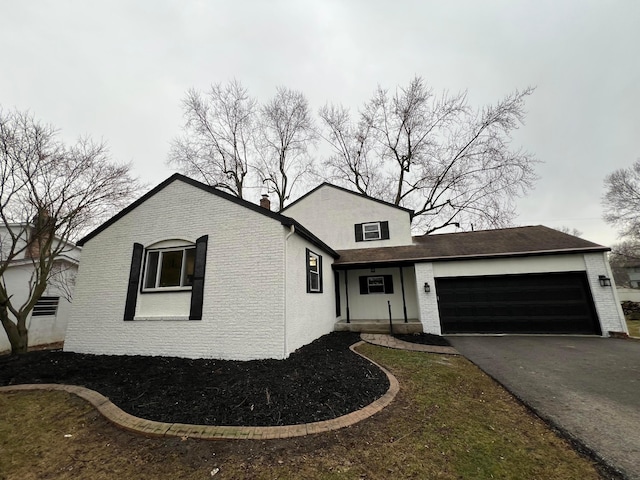 view of front facade featuring an attached garage, aphalt driveway, and brick siding