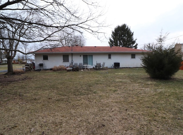 rear view of house featuring central AC unit and a yard