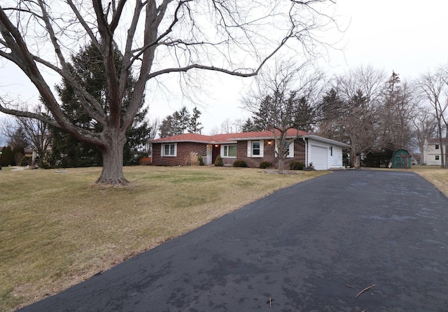 ranch-style house featuring a garage, driveway, a front lawn, and brick siding