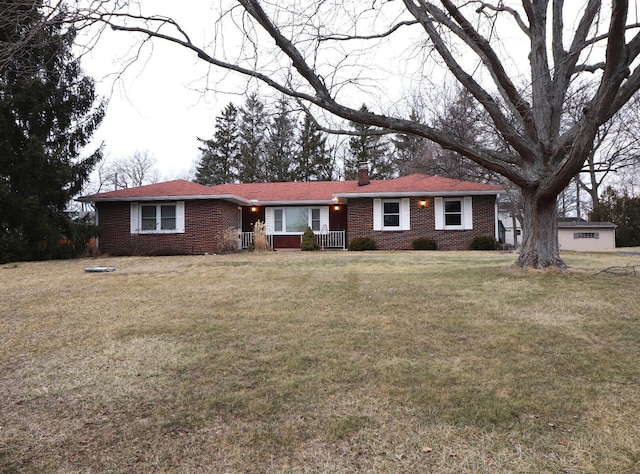 ranch-style house featuring brick siding, a chimney, and a front yard