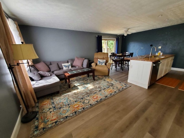 living area featuring ceiling fan, baseboards, and dark wood-style flooring