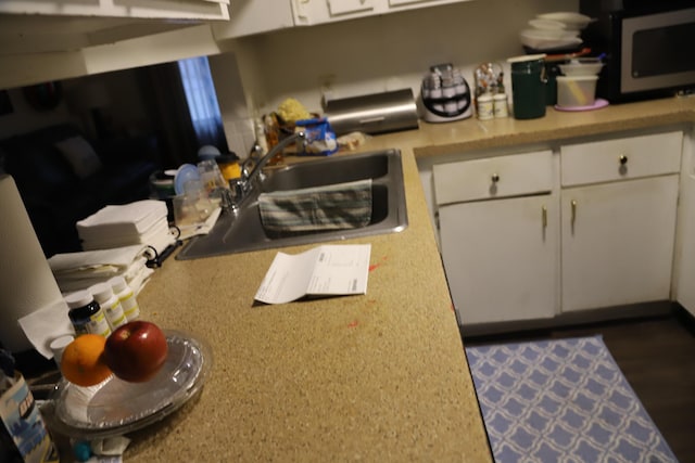 kitchen featuring white cabinetry, light countertops, and a sink