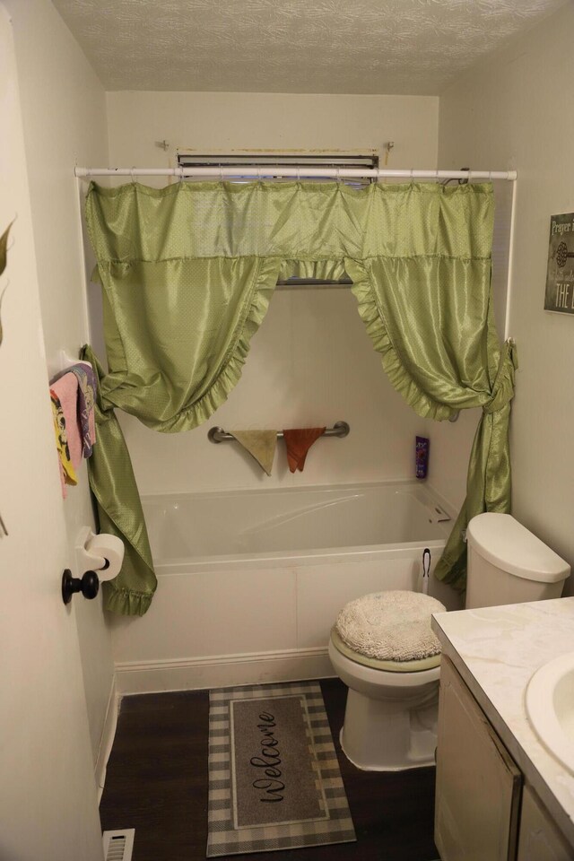 full bathroom with shower / bath combo with shower curtain, a textured ceiling, toilet, and vanity