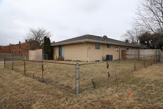 view of side of property with fence, a lawn, and central AC