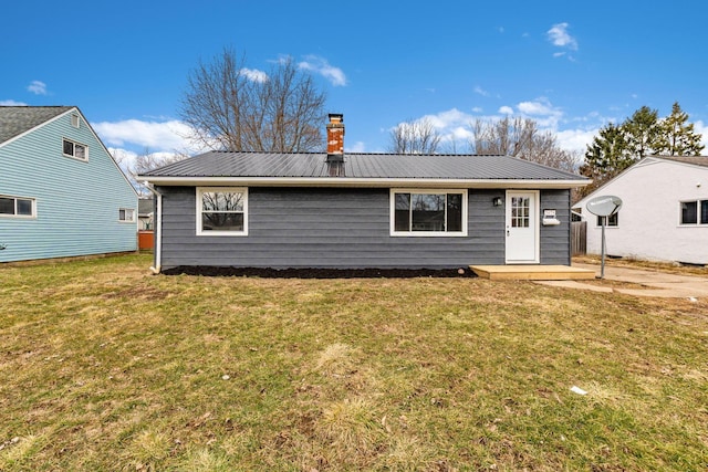 back of house featuring metal roof, a yard, and a chimney