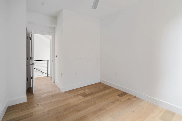 spare room with ceiling fan, light wood finished floors, and baseboards