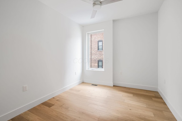 empty room with a ceiling fan, light wood-type flooring, visible vents, and baseboards