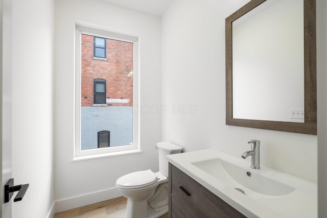 bathroom featuring vanity, wood finished floors, toilet, and baseboards