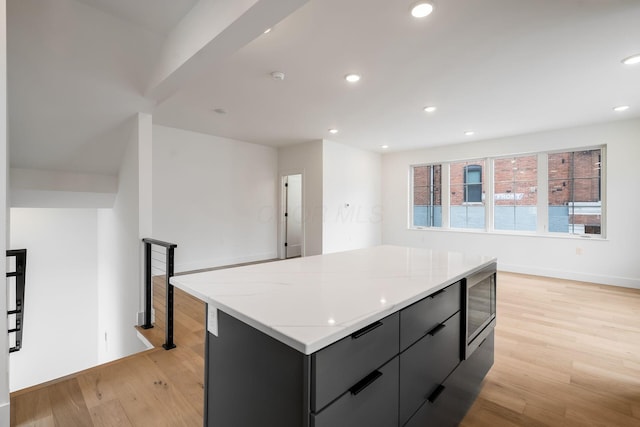 kitchen with dark cabinets, recessed lighting, a center island, and light wood-style floors