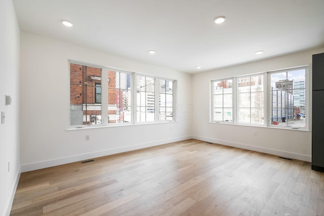 empty room with recessed lighting, visible vents, light wood-style flooring, and baseboards