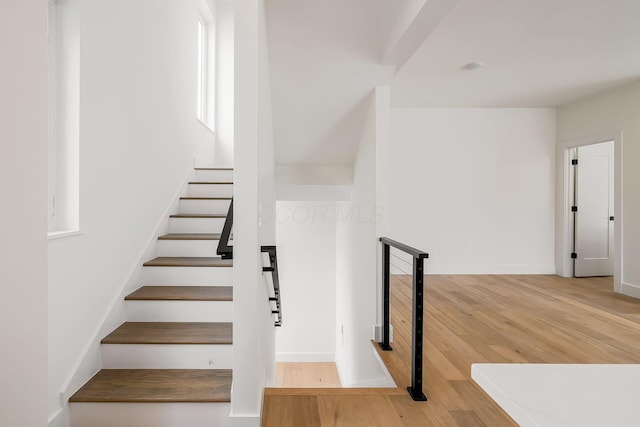 stairs with wood finished floors and baseboards