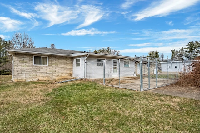 back of house featuring stone siding, a lawn, and fence