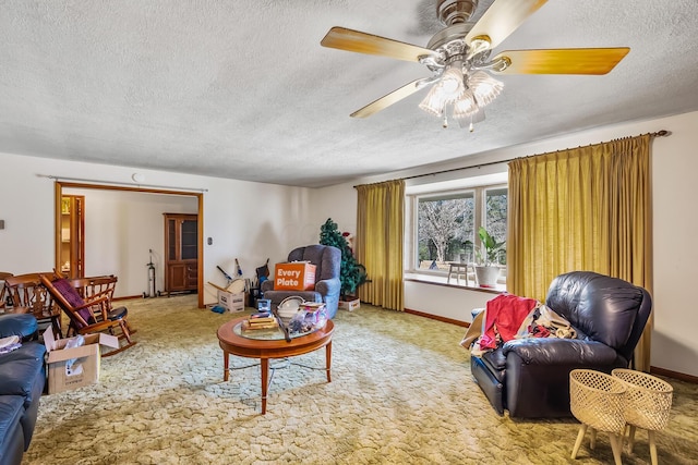 living area with carpet floors, ceiling fan, baseboards, and a textured ceiling