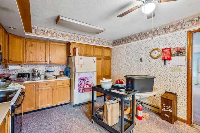 kitchen with a textured ceiling, light countertops, freestanding refrigerator, electric range oven, and wallpapered walls