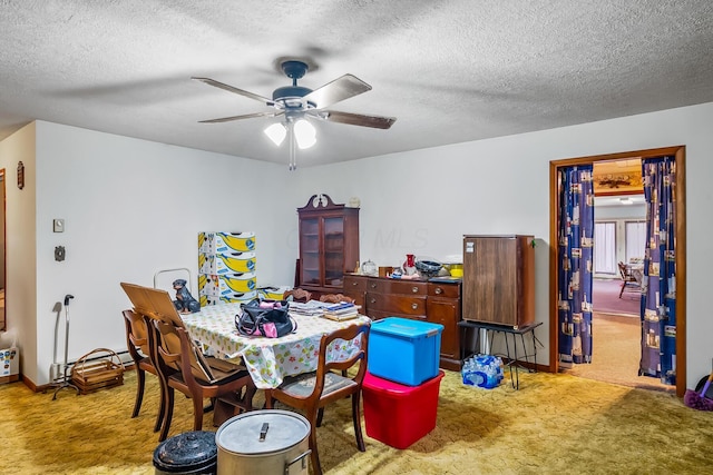 dining space with a textured ceiling, carpet, a ceiling fan, and baseboards