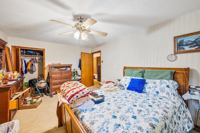 carpeted bedroom featuring a textured ceiling, a closet, and a ceiling fan