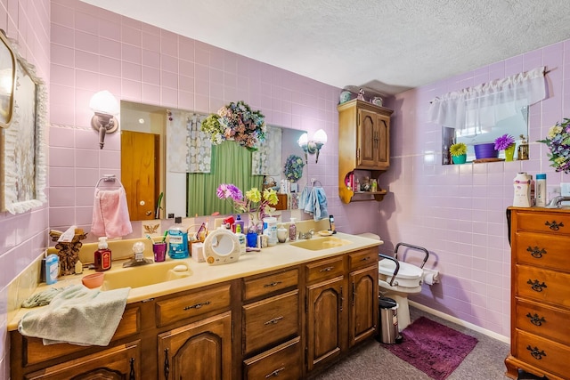 full bath featuring a textured ceiling, a sink, and tile walls