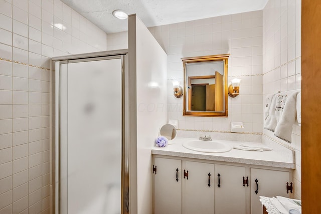 full bath featuring a stall shower, vanity, tile walls, and backsplash