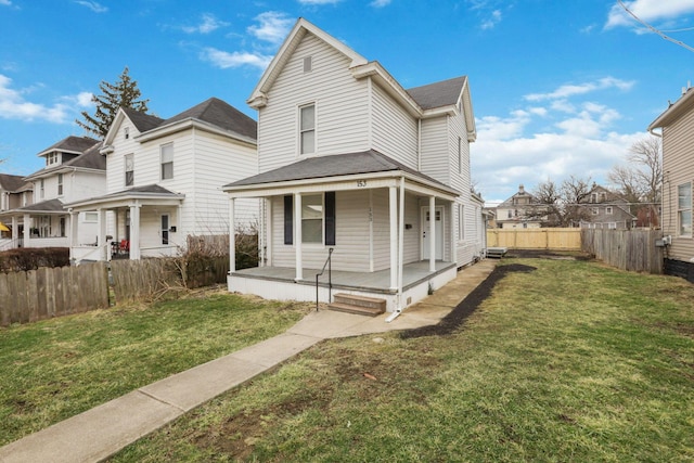 view of front facade with covered porch, a residential view, fence, and a front lawn