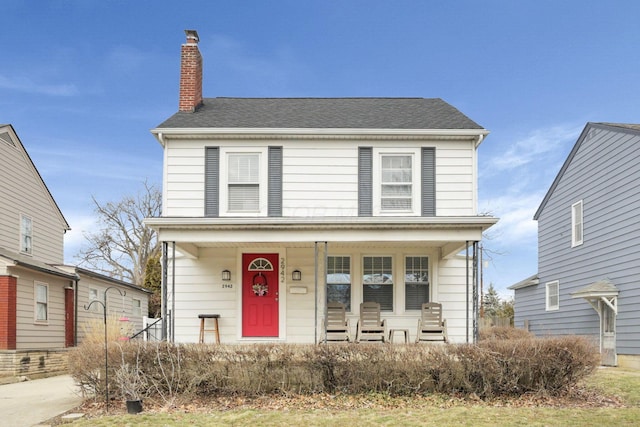 american foursquare style home with covered porch and a chimney