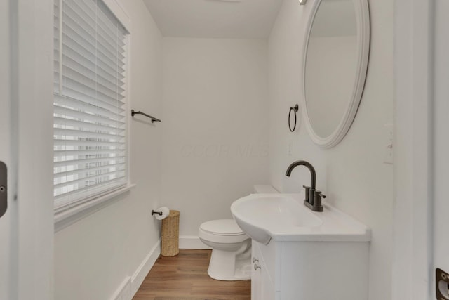 bathroom with vanity, wood finished floors, toilet, and baseboards