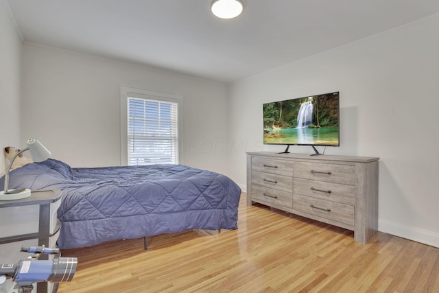 bedroom featuring crown molding, light wood finished floors, and baseboards