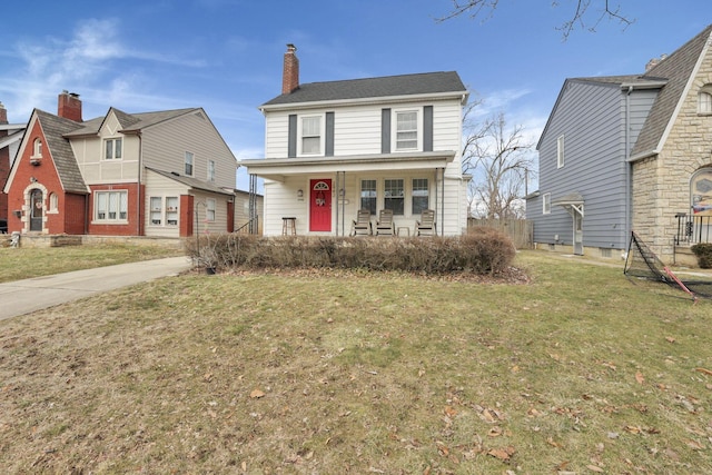 traditional-style house with driveway, a porch, a chimney, and a front yard