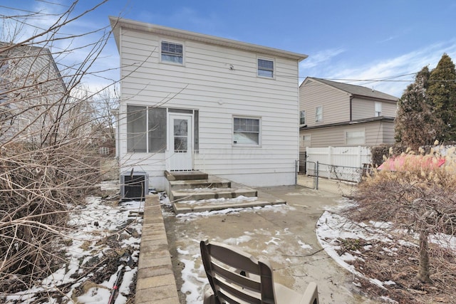 snow covered house with central AC and fence