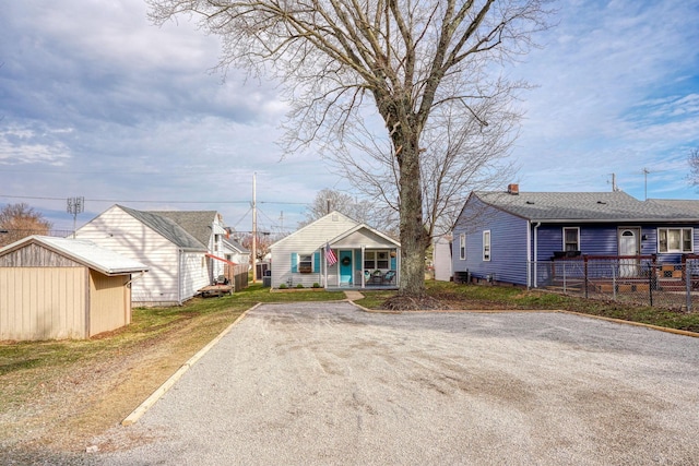 bungalow-style home featuring fence, a porch, and an outbuilding