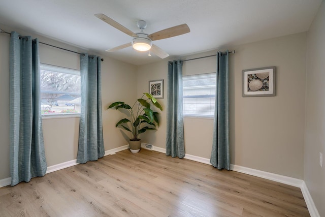 empty room featuring light wood-style flooring, visible vents, baseboards, and a ceiling fan