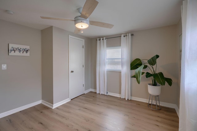 spare room featuring ceiling fan, light wood-type flooring, and baseboards