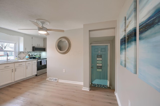 kitchen with stainless steel appliances, a sink, visible vents, white cabinets, and light wood-type flooring